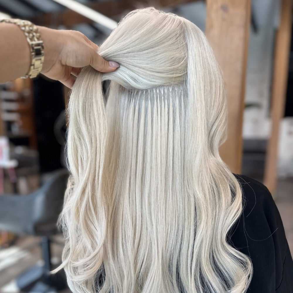 Long platinum blonde hair with extensions being styled in a salon setting.